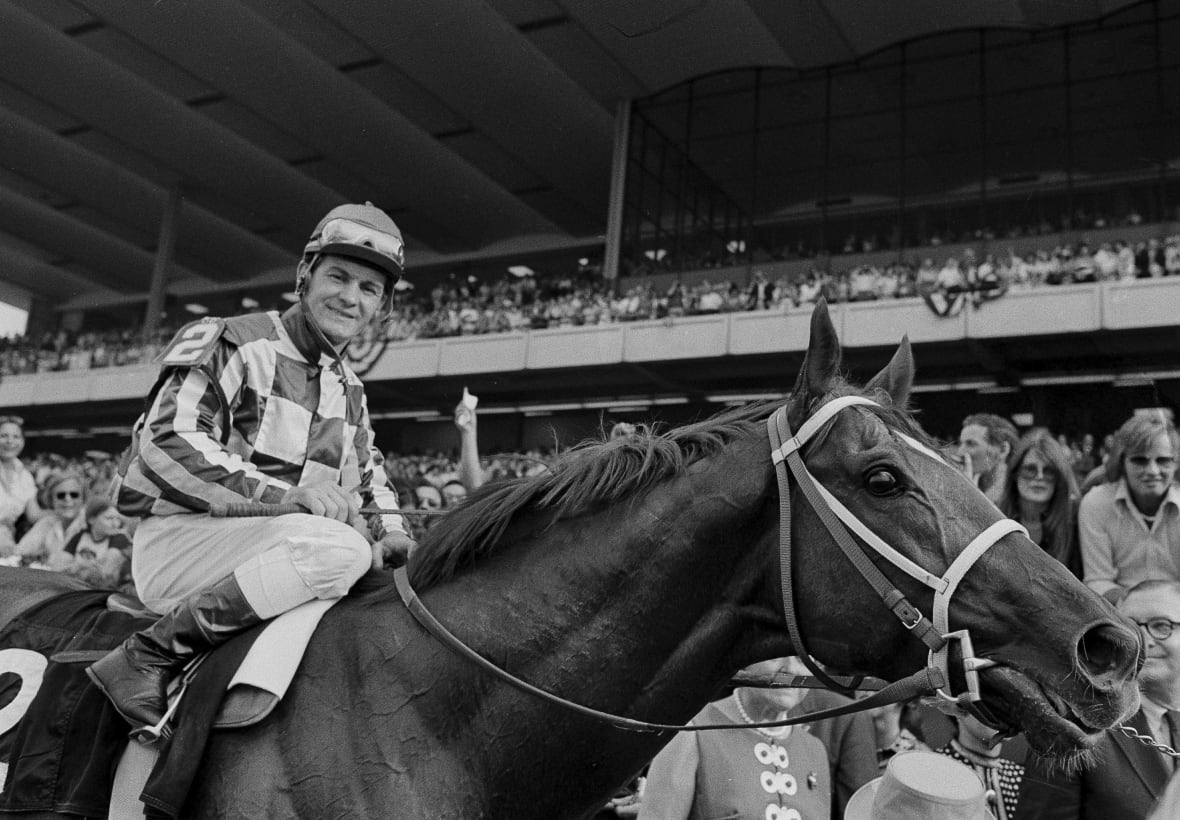A black-and-white photo shows a jockey on a horse.