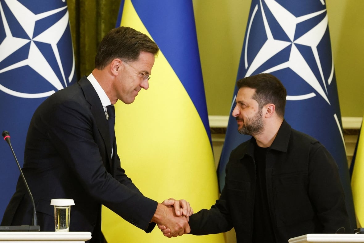 Two men shake back in front of the Ukrainian flag