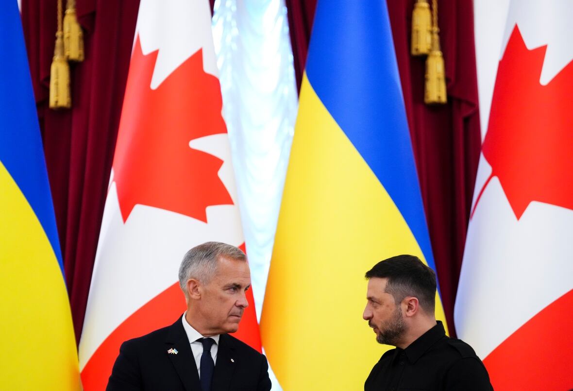 Two men speak to each other in front of Canadian and Ukrainian flags.