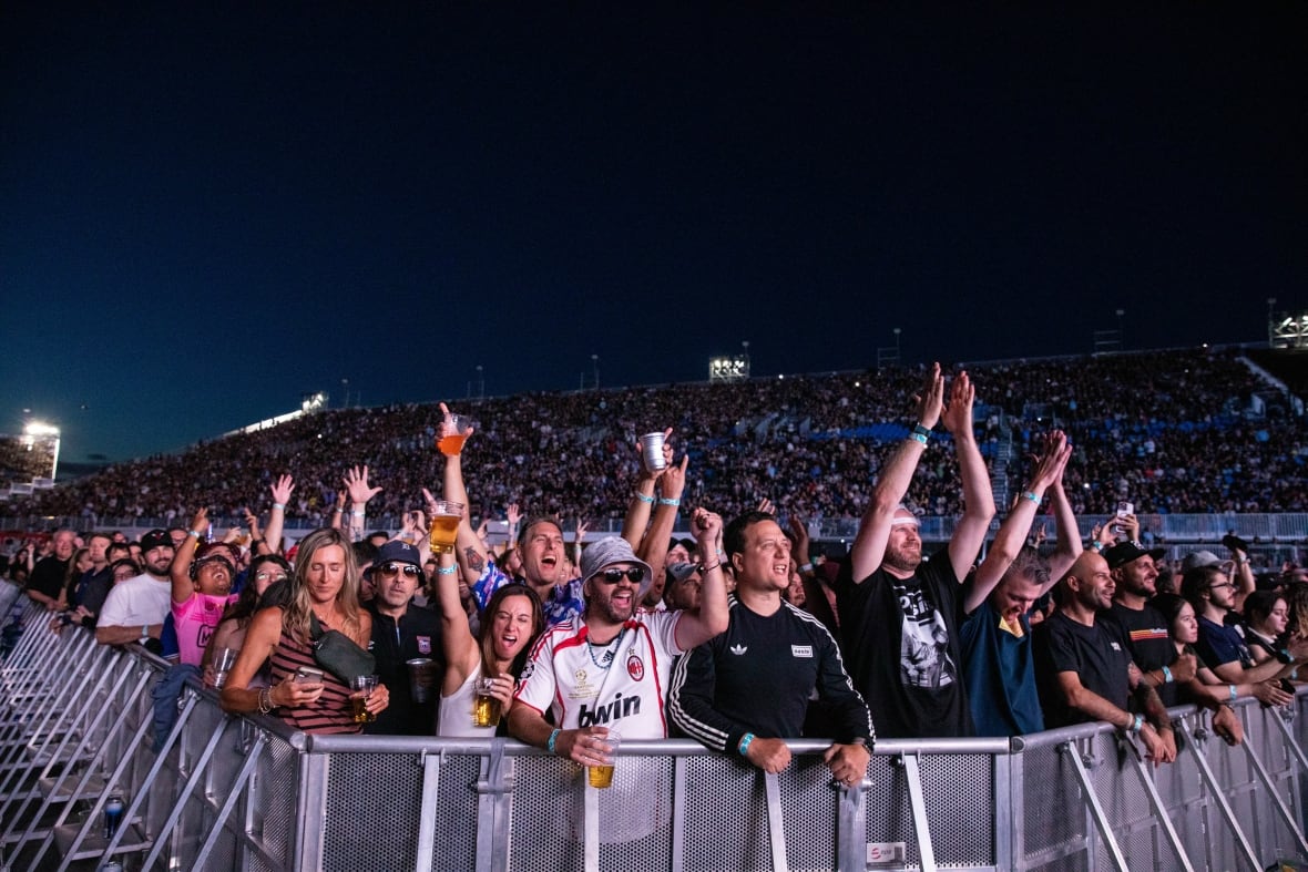 A group of fans behind a barrier cheer.