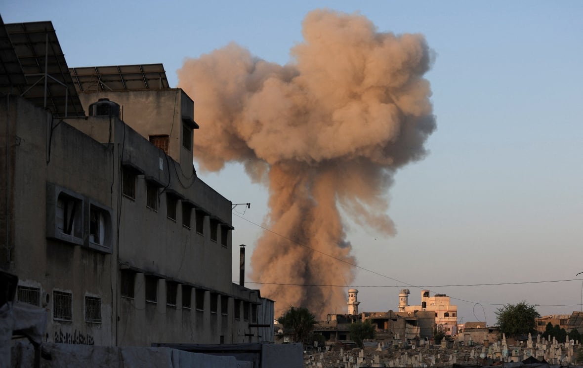 The great cloud of smoke is shown in the blue sky near the buildings.