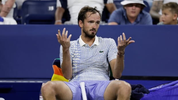 A man in a tennis outfit shrugs