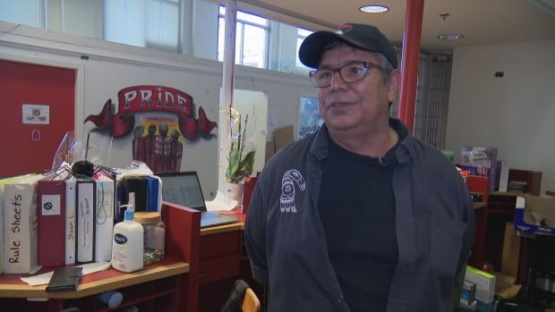 Aboriginal Front Door Society faces scaling back its storage program for unhoused DTES residents, or even closure. It's because the province says it hasn't found long term funding for the initiative, says Chris Livingstone, executive director on August 18, 2025, Indigenous man with a ballcap and glasses is pictured in front of a mural that says pride.