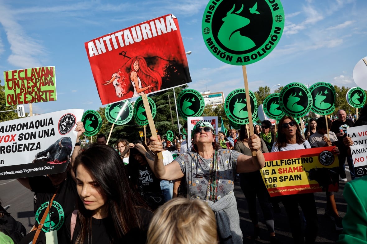 People in a crowd carry signs with bulls and write on them