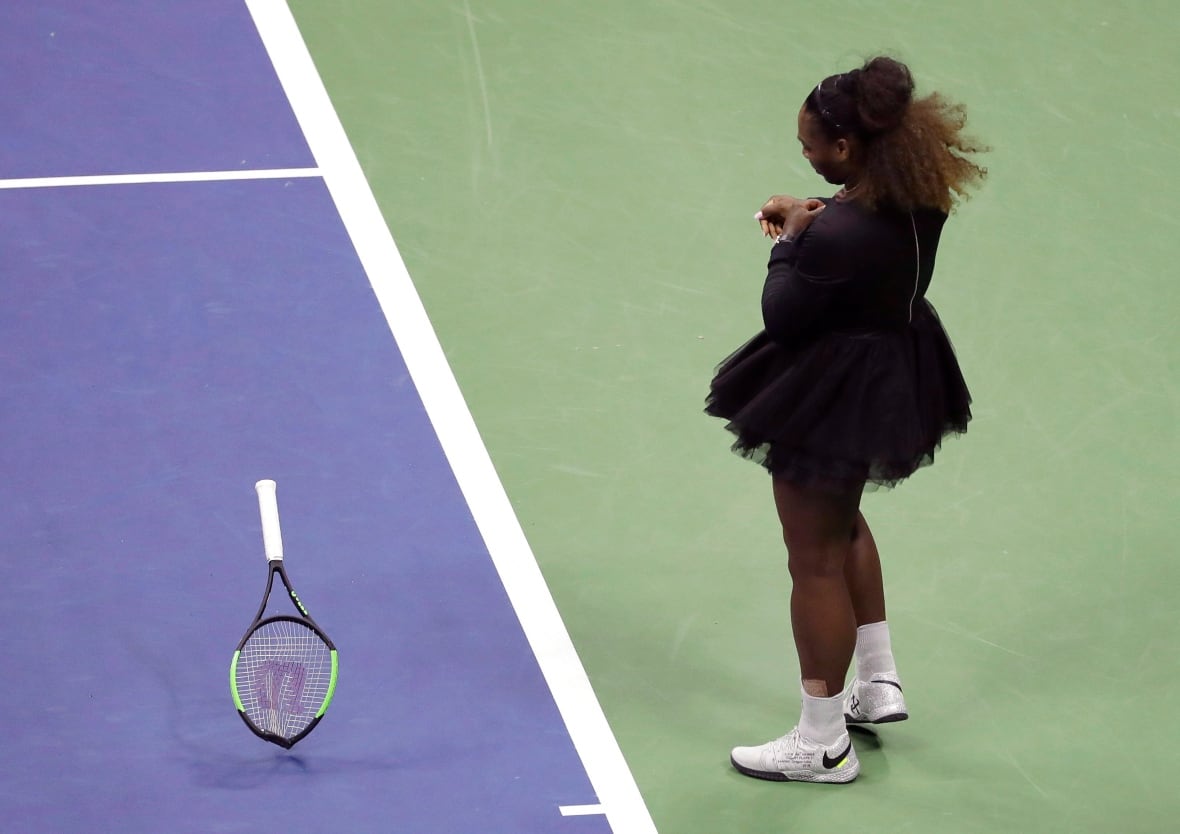 The woman dressed in a black throwing tennis racket