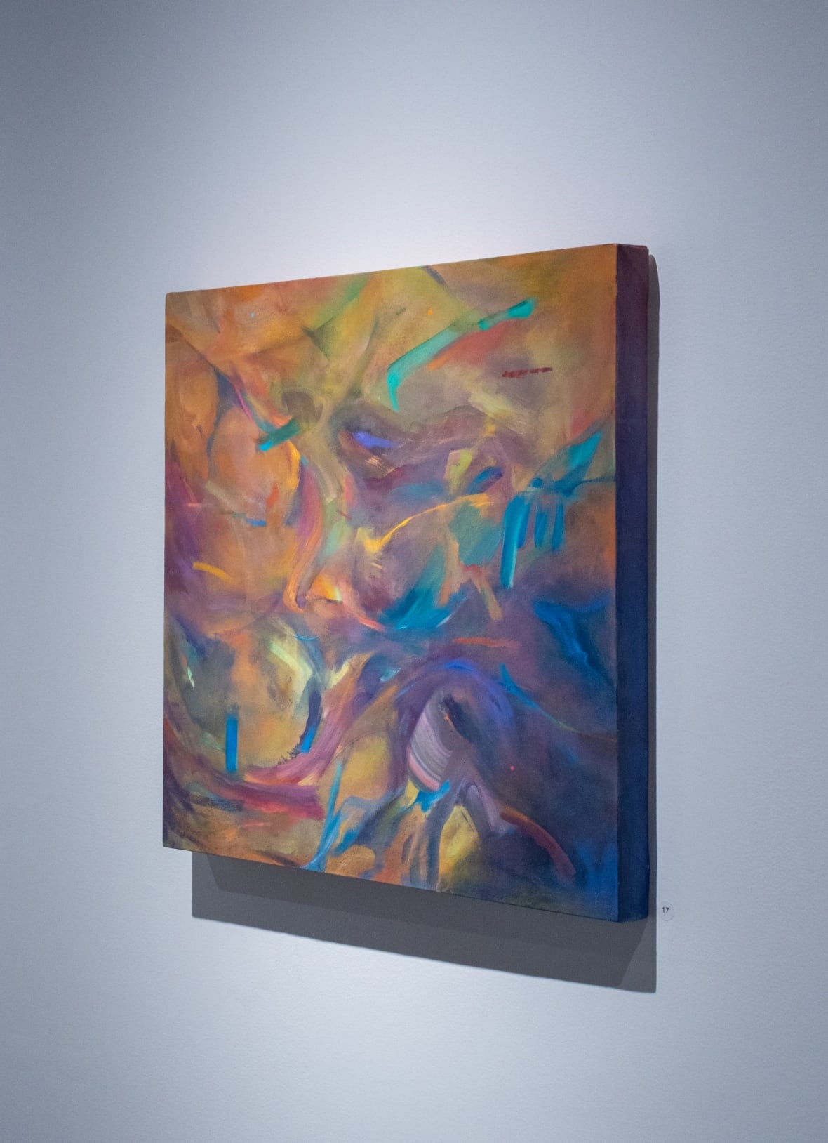 The abstract paintings shows a swirl of colours, dominated by blues, purples and oranges.