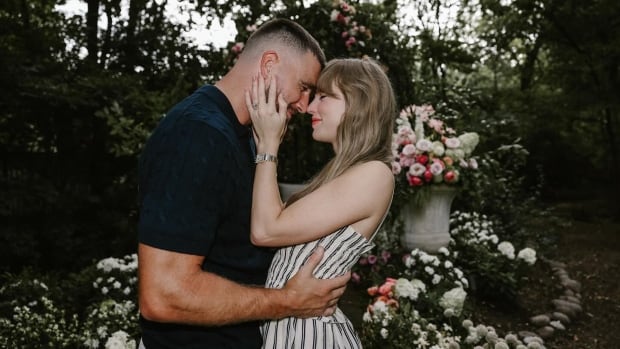A man and a woman embrace in a  flower filled garden