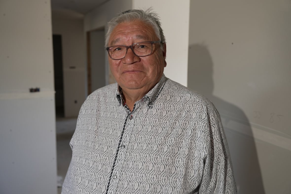 Smiling older man with grey hair in button up shirt wearing glasses