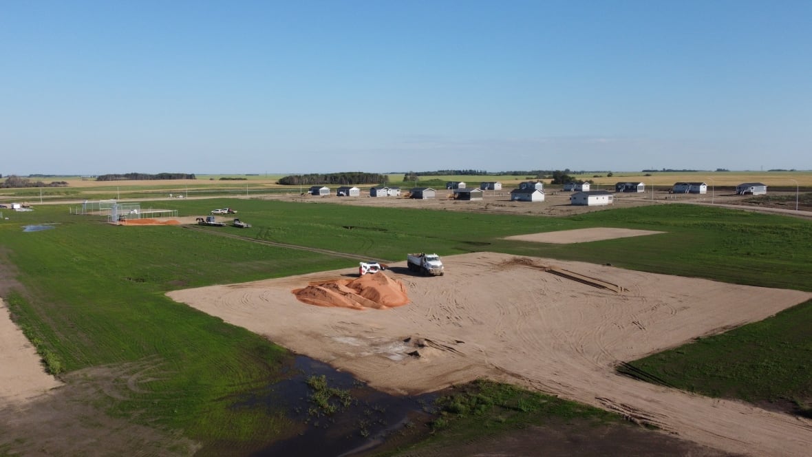 Construction equipments builds a softball diamond with 14 new houses in the background