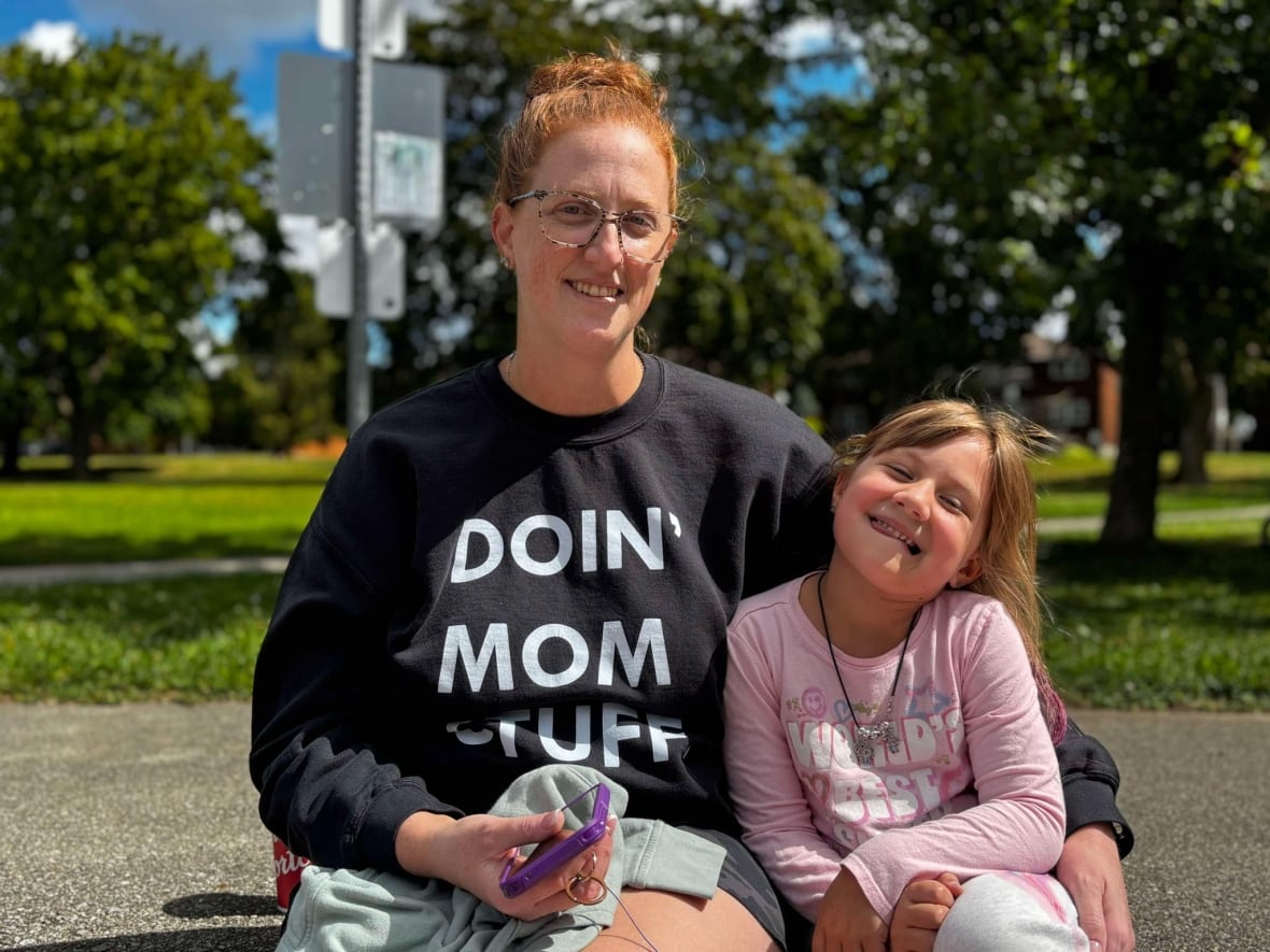 A mom and daughter smile at the camera