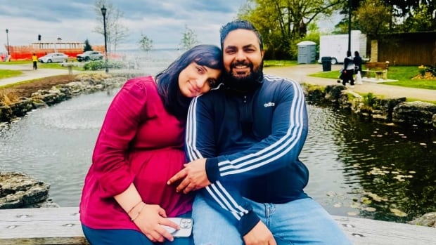Ravinder Kaur Sidhu sits on a bench next to her husband with her head on his shoulder. 