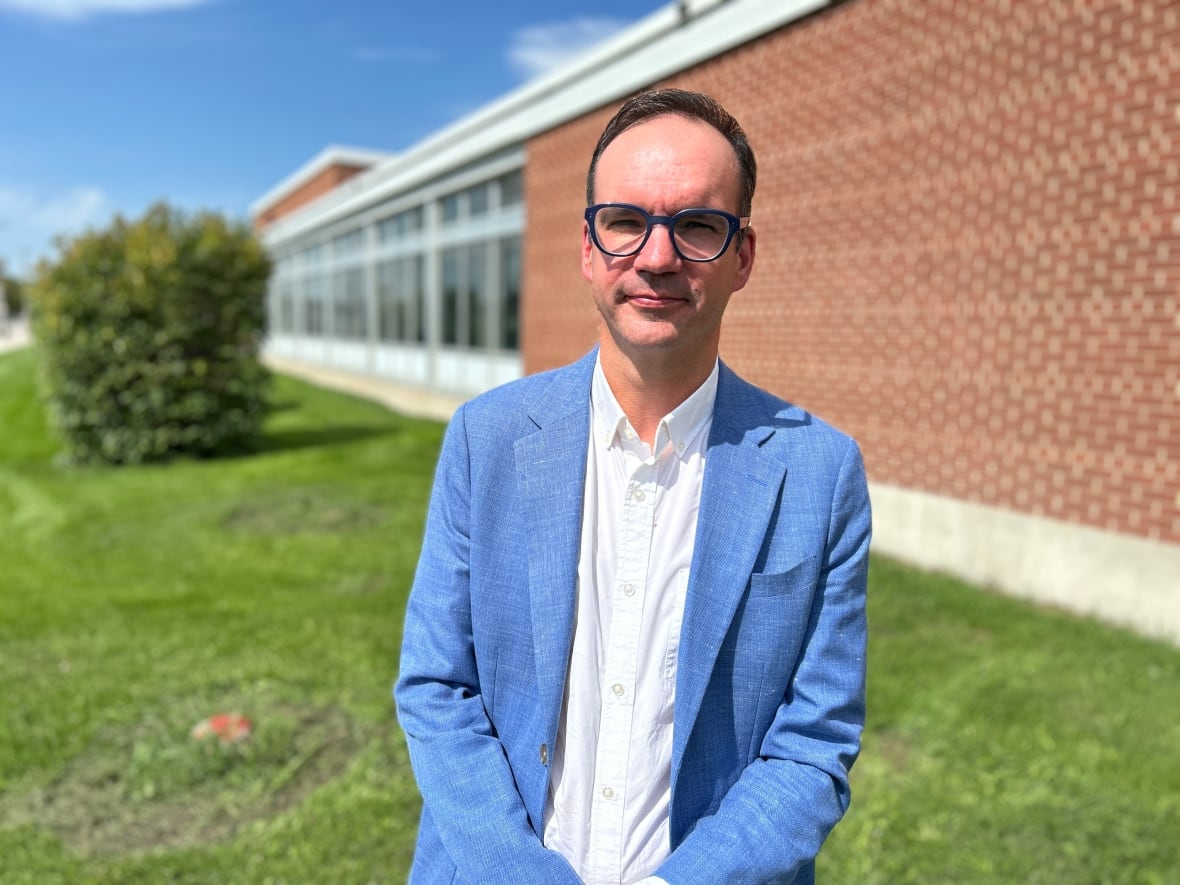 A person is wearing a blue blazer a glasses.