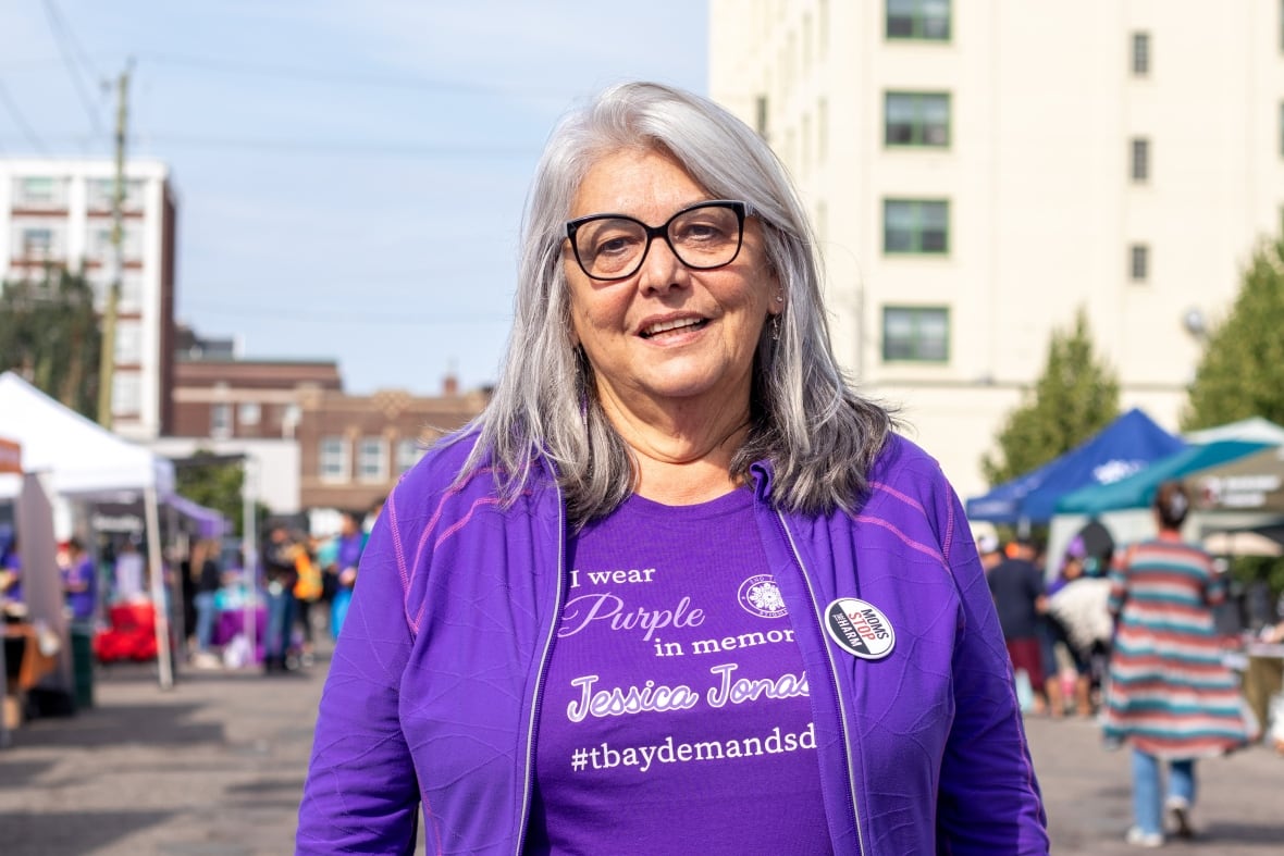 A person wearing purple is seen standing on a street.