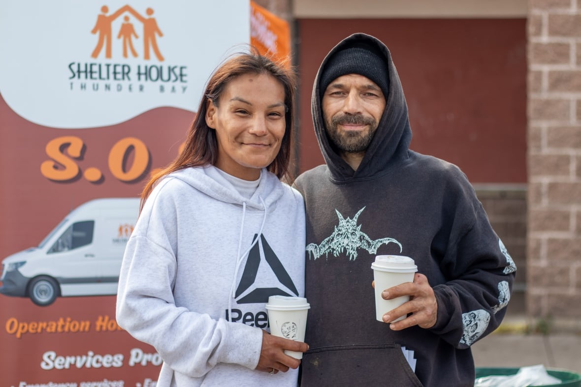 Two people are seen outside, holding coffee cups.