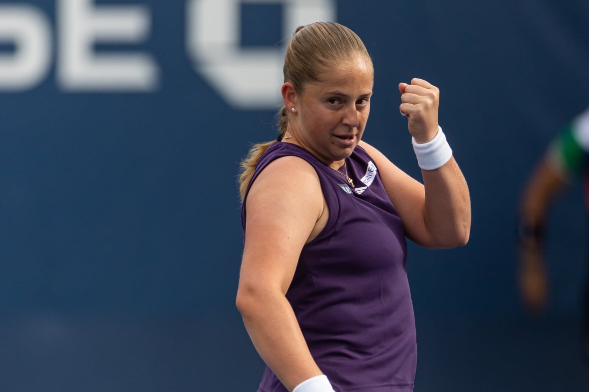 A woman in tennis clothes pumps her fist