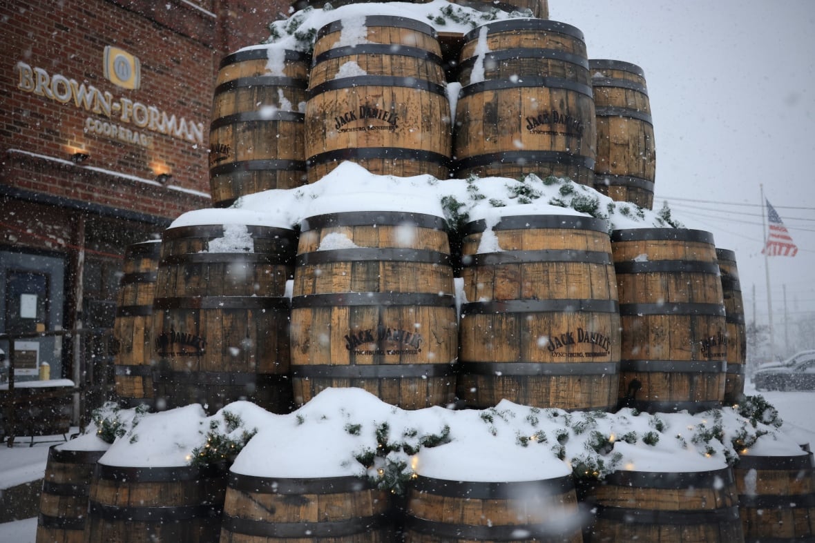 A pile of snow -covered whiskey barrels is displayed.