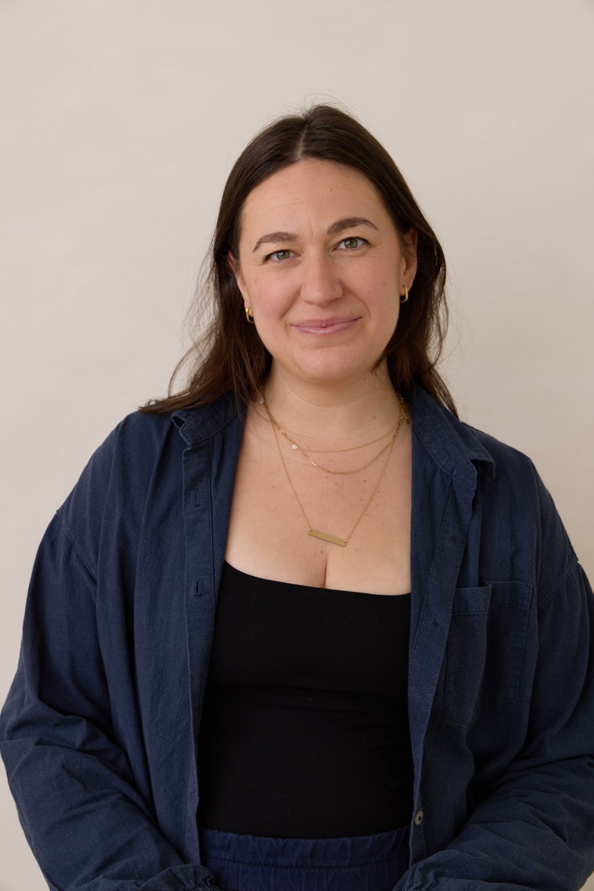 A woman wearing a black shirt and a blue coat is photographed.