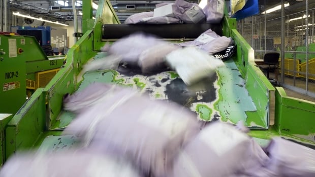 Several packages slide down a ramp at a mail inspection facility.