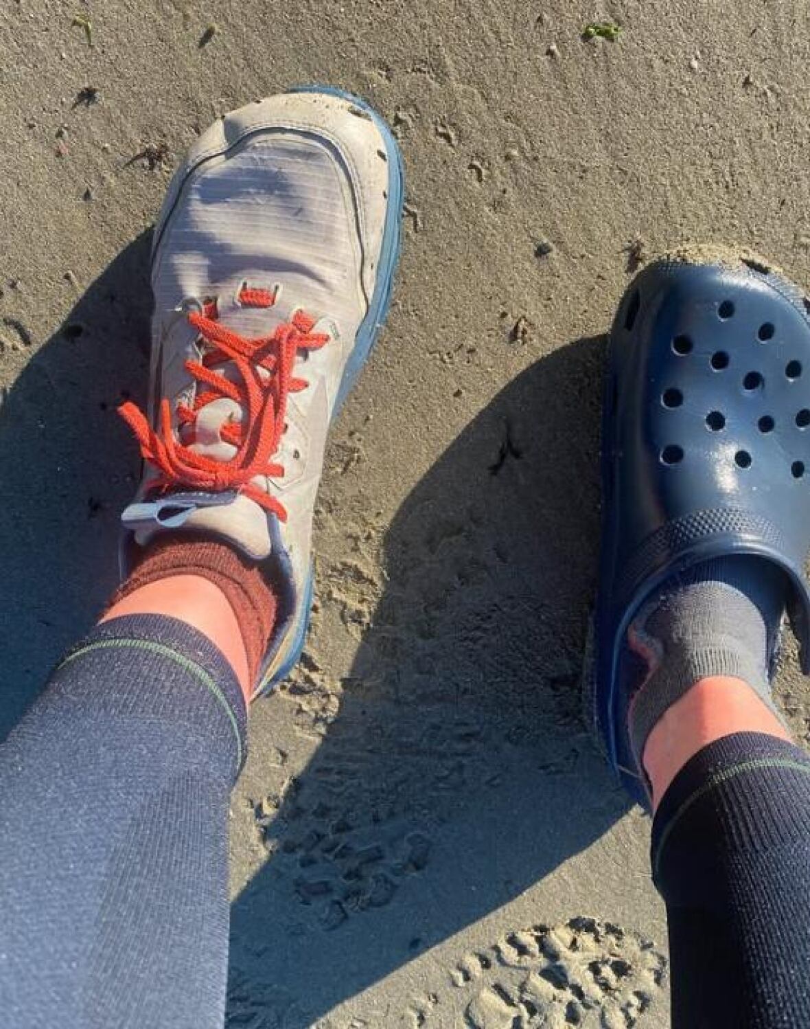 A person wears a running shoe and a croc