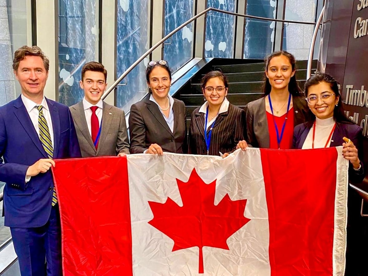 People standing behind a large Canadian flag.