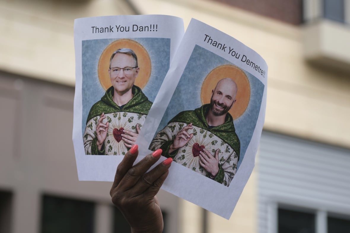 The person holds pictures depicting the faces of two CDC leaders who resigned from the US Public Health Agency.