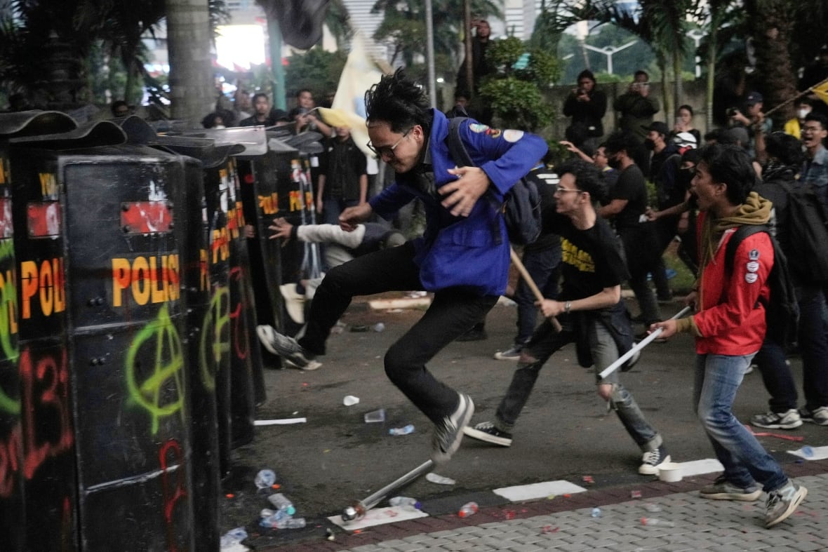 People run and jump toward a riot policewoman