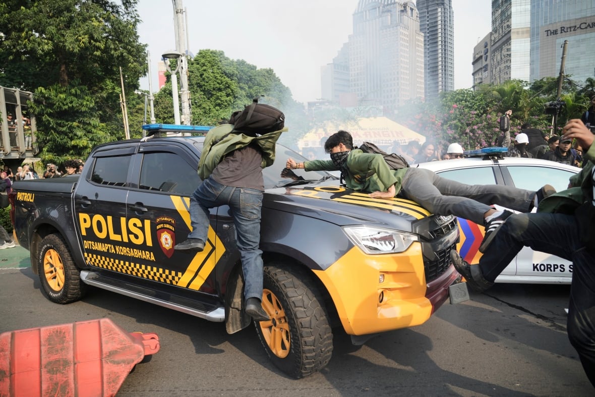 People in the green jackets throw themselves at the police car