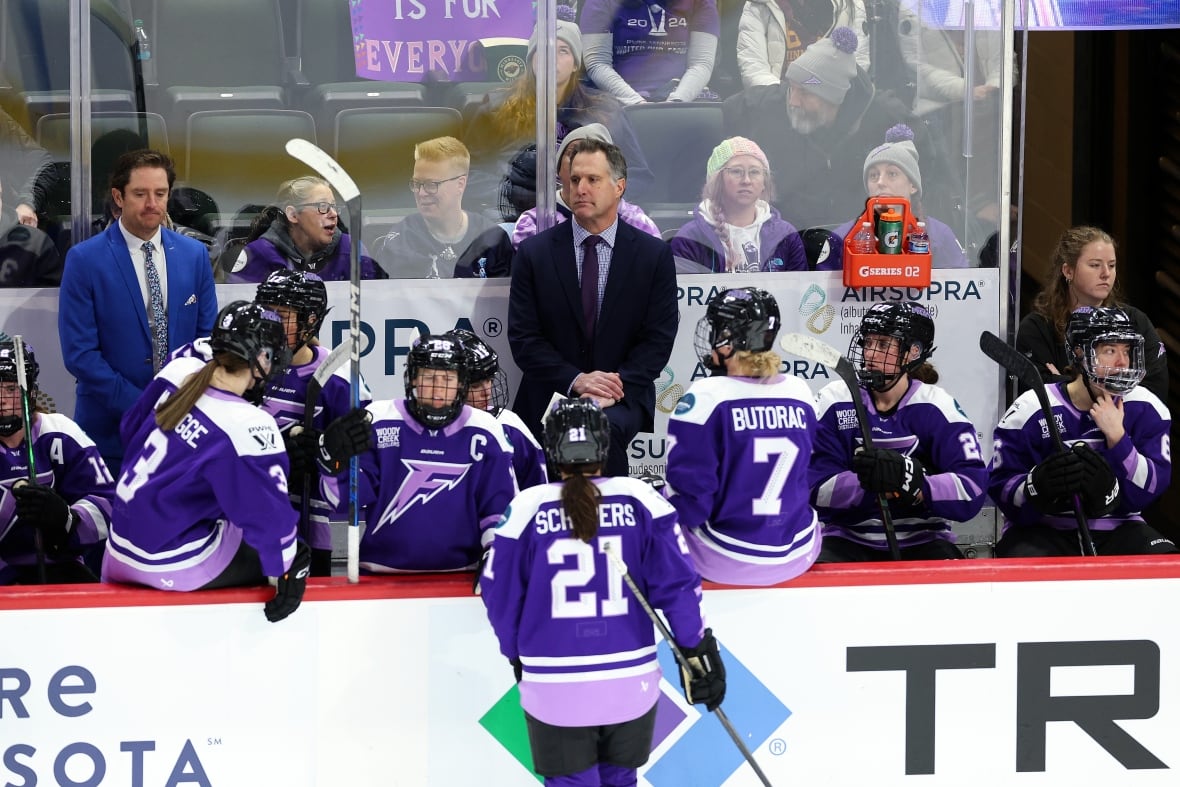 Coach Ken Klee stands in the middle of the Minnesota Frost's bench during a pause in play. 