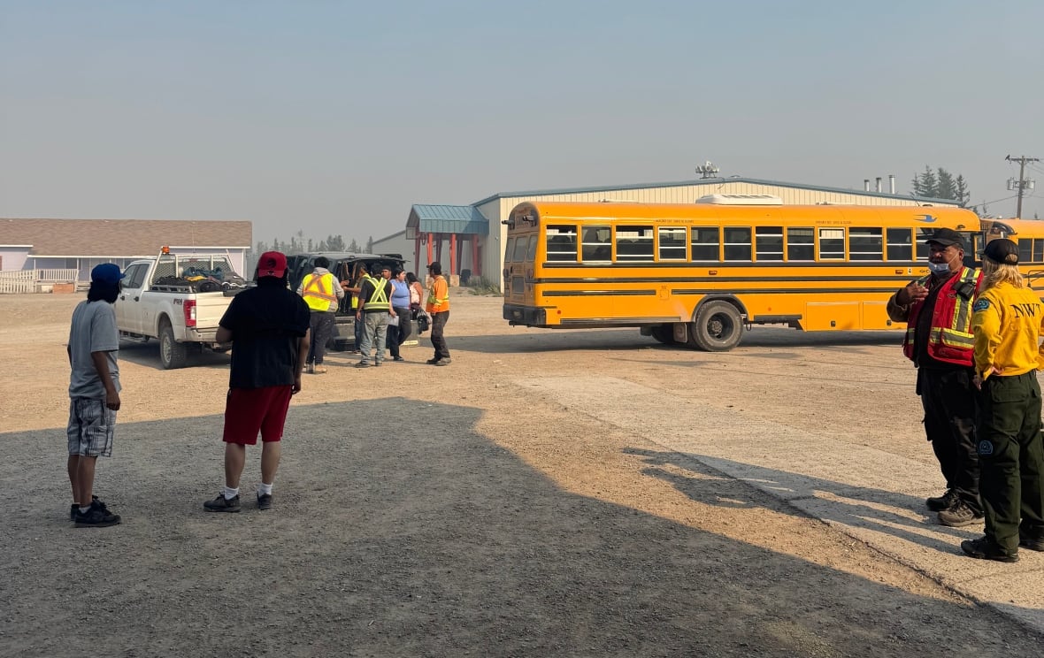 A school bus with people standing. Some with Hi-Viz clothes.