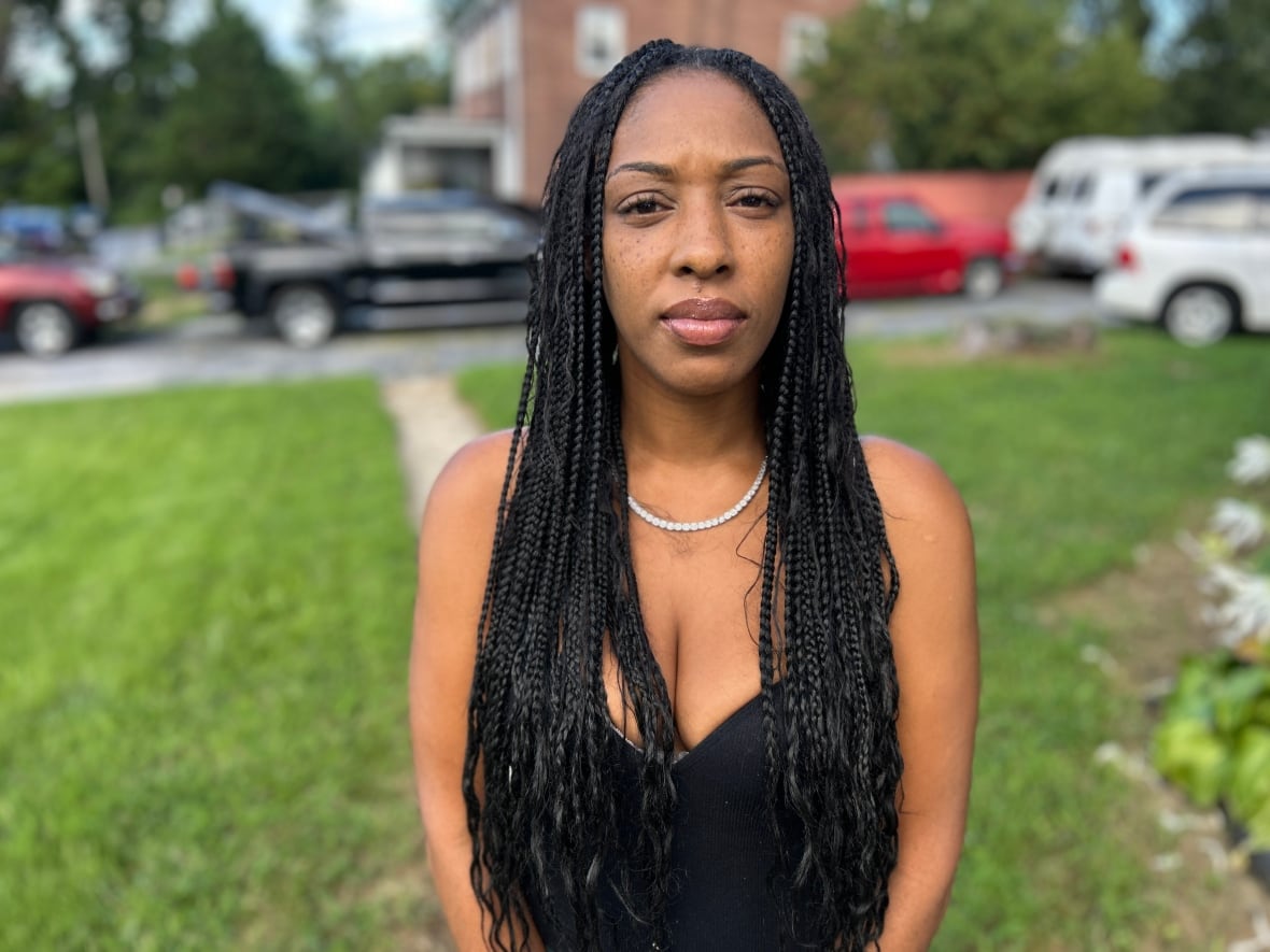 Jawanna Hardy is an African American woman with long black hair. It stands in front of the grass, wearing a black tank summit.