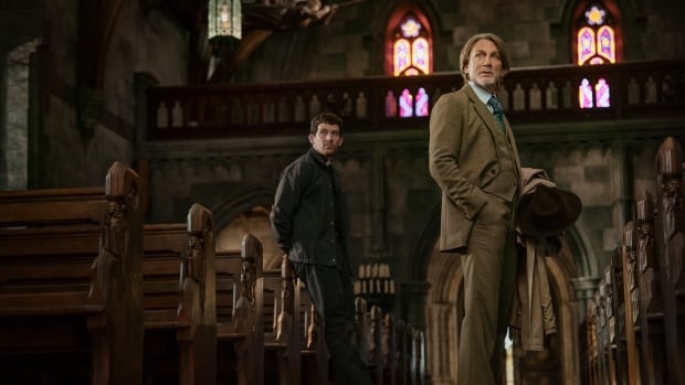 Two men stand in a church.