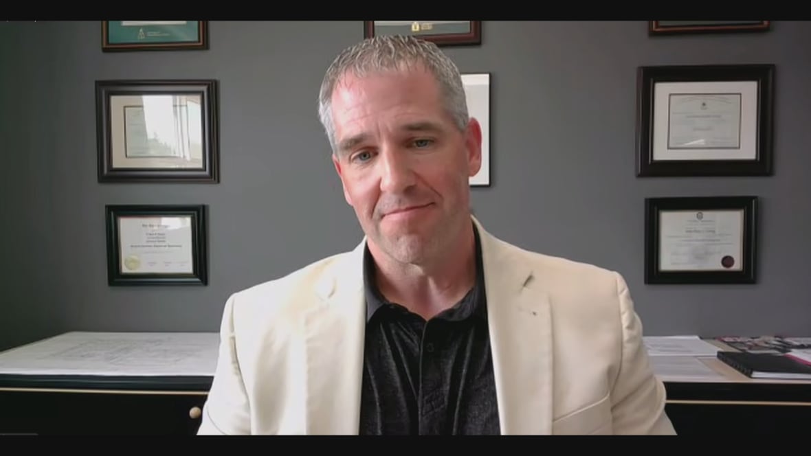 A man with a white suit jacket and a black neck shirt.