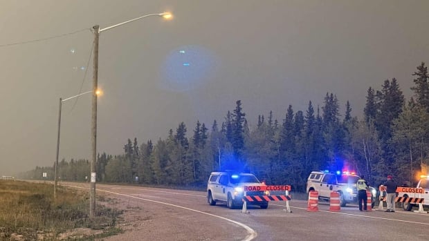 A photo of a check stop on Highway 3 near Fort Providence. The road, which goes towards Yellowknife, was closed on Saturday do to a wildfire. Police and road closed signs along a highway.