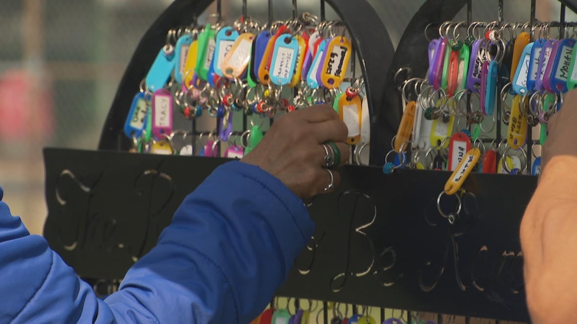 People touch a wall of colourful keyrings.