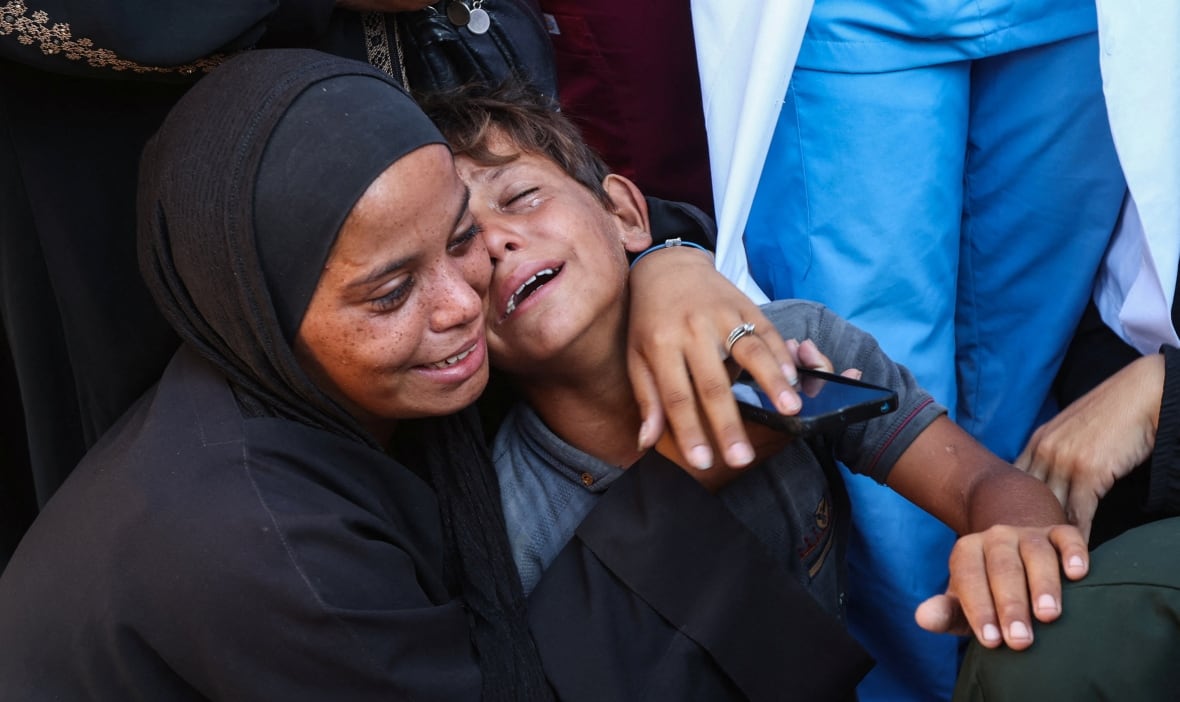 The woman holds a young boy as you both cry. Some of my people nearby, their legs are visible. 