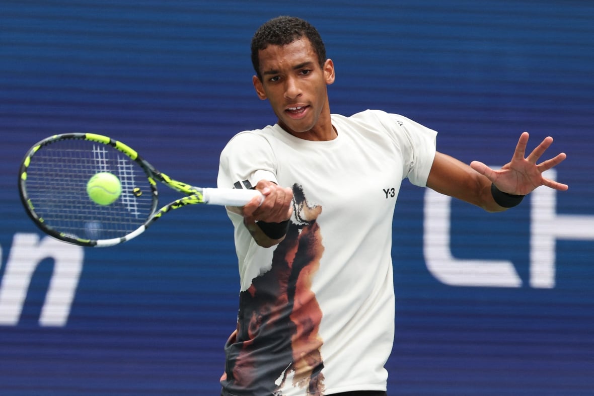 A male tennis player plays a forehand return with the racket in his right hand.