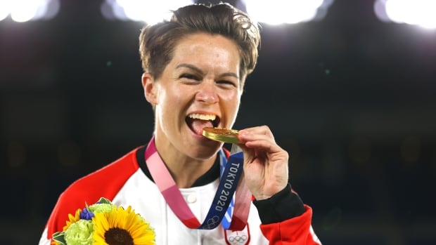 A woman bites a gold medal.