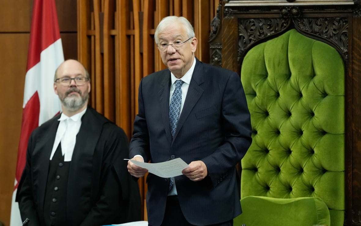 A man in a suit holds a piece of paper as he speaks in the House of Commons.