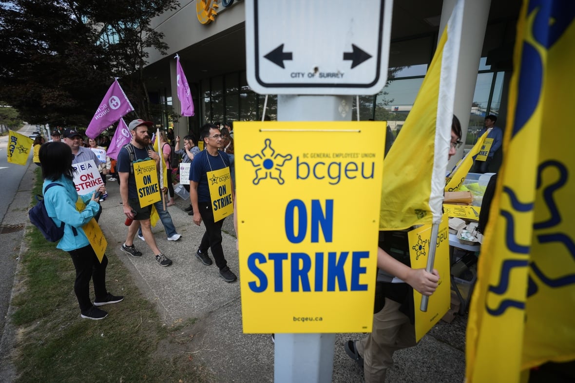 A yellow sign on a sign reads, 'BCGEU On Strike.'