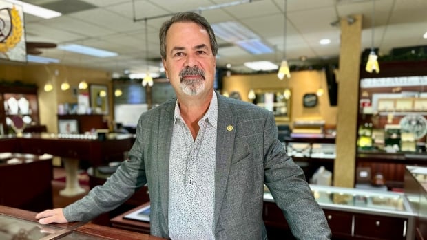 man stands at counter of jewelry store.