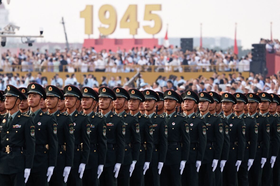 The same line of soldiers in dark green suits and hats walked before the crod on bleachers and a sign saying in 1945.