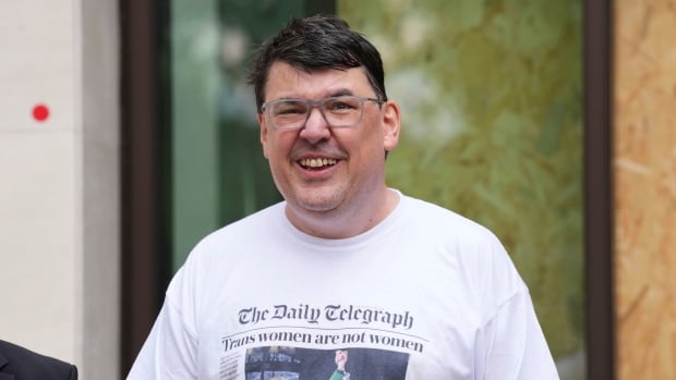 Television comedy producer Graham Linehan is shown on May 12 in London, wearing a T-shirt celebrating a recent U.K. Supreme Court ruling. A dark haired cleanshaven man wearing glasses is shown smiling while wearing a t-shirt.