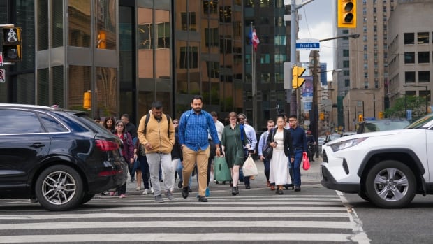 People walk through a busy downtown intersection.