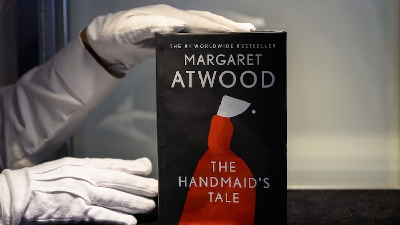 A white gloved hand holds up a book.