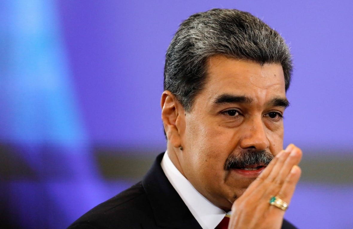 A mustache man holds his hand giving a speech.