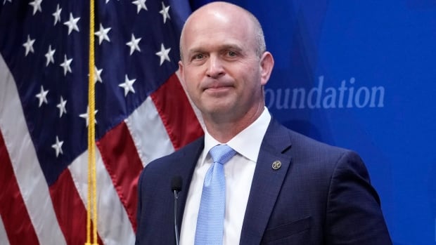A man stands in front of an American flag.