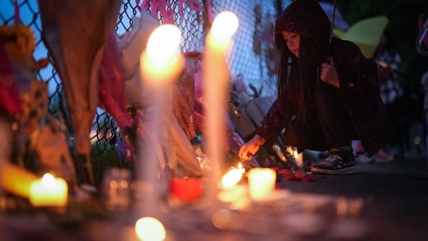 A young girl lights a candle during a vigil.