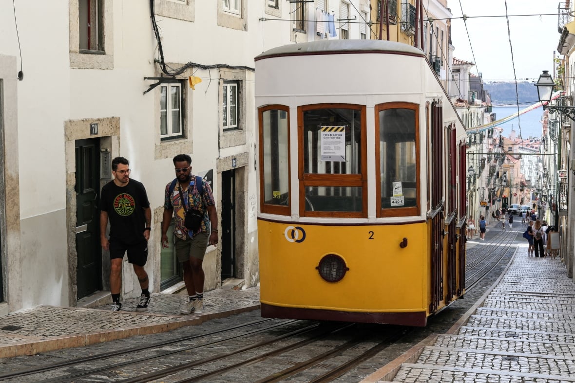 A yellow train car on a sharp street.