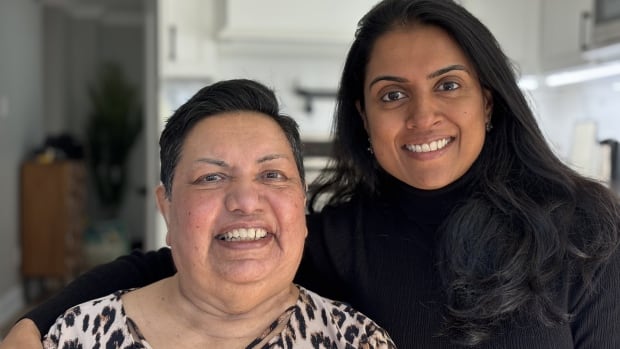 A portrait of a mother and daughter smiling at the camera