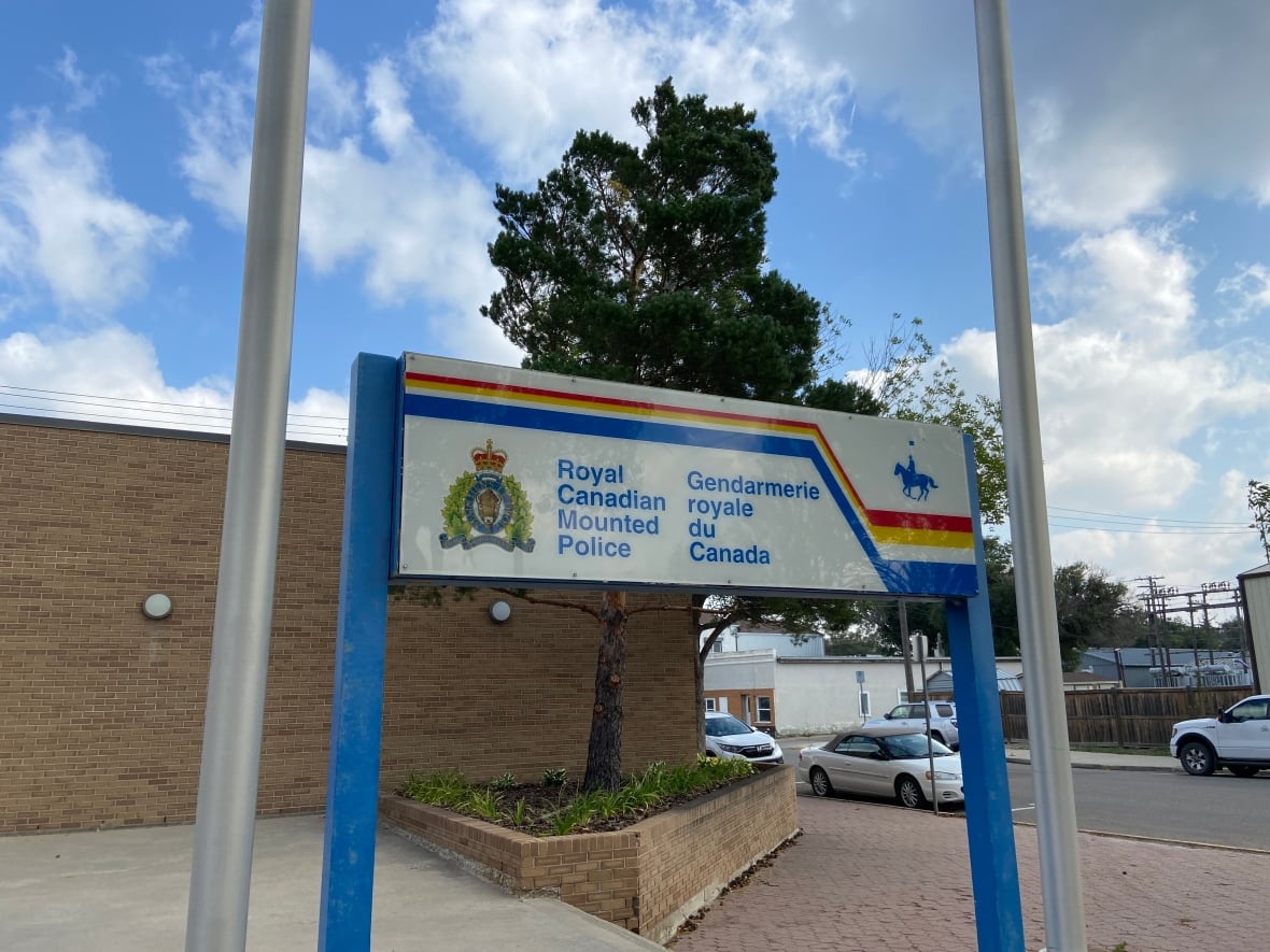 Photo of a sign outside of a brick building, flanked by two flag poles. The sign reads "Royal Canadian Mounted Police."